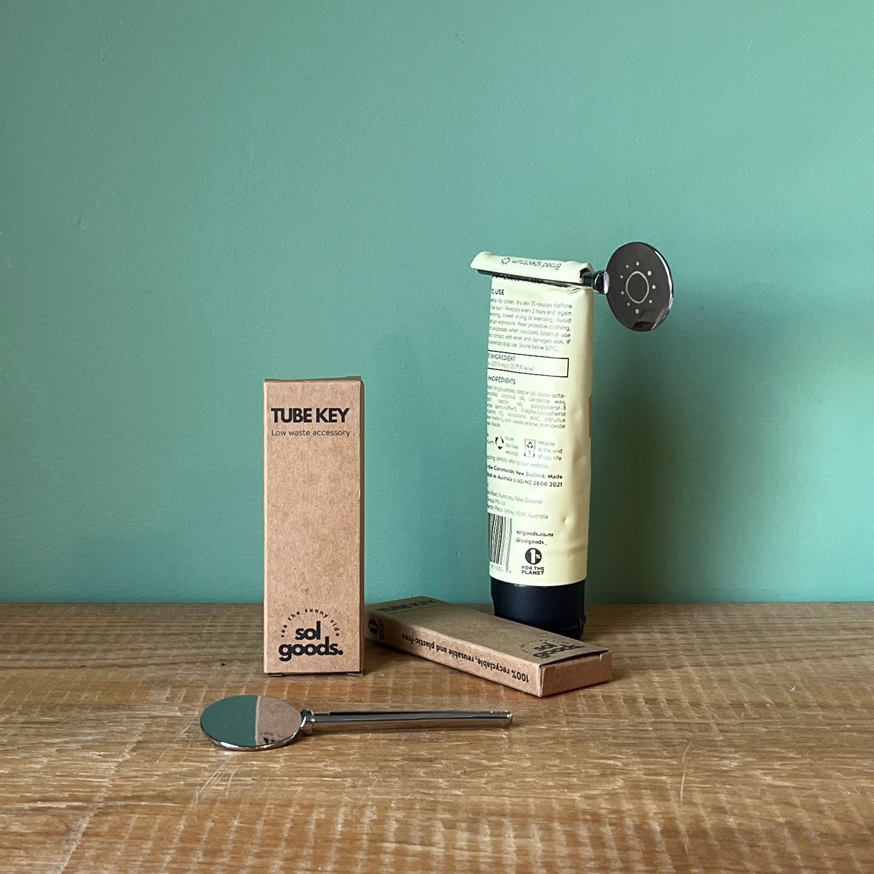 Tube of cream with packaging and a spoon on a wooden surface against a teal wall
