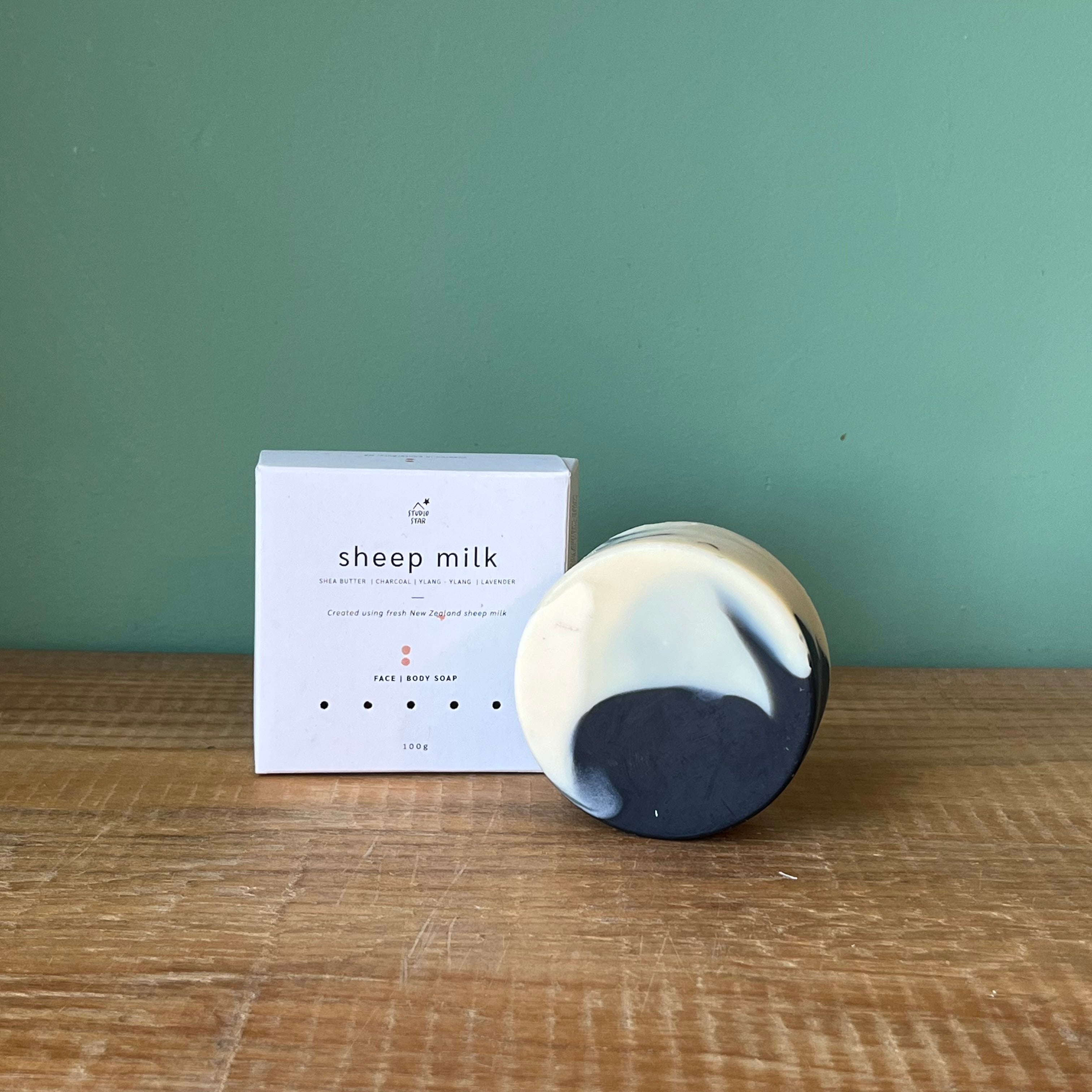 Sheep milk product with packaging on a wooden surface against a green wall